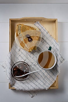 Pancakes Russian Blini with strawberry jam and tea on a tray. Breakfast. ÃÂ¡lose up. ÃÂ¢op view